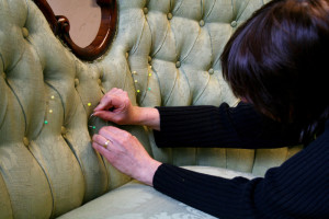 Katarina nålar en möbel inne på Bagarmossens tapetserare i Bagarmossen
